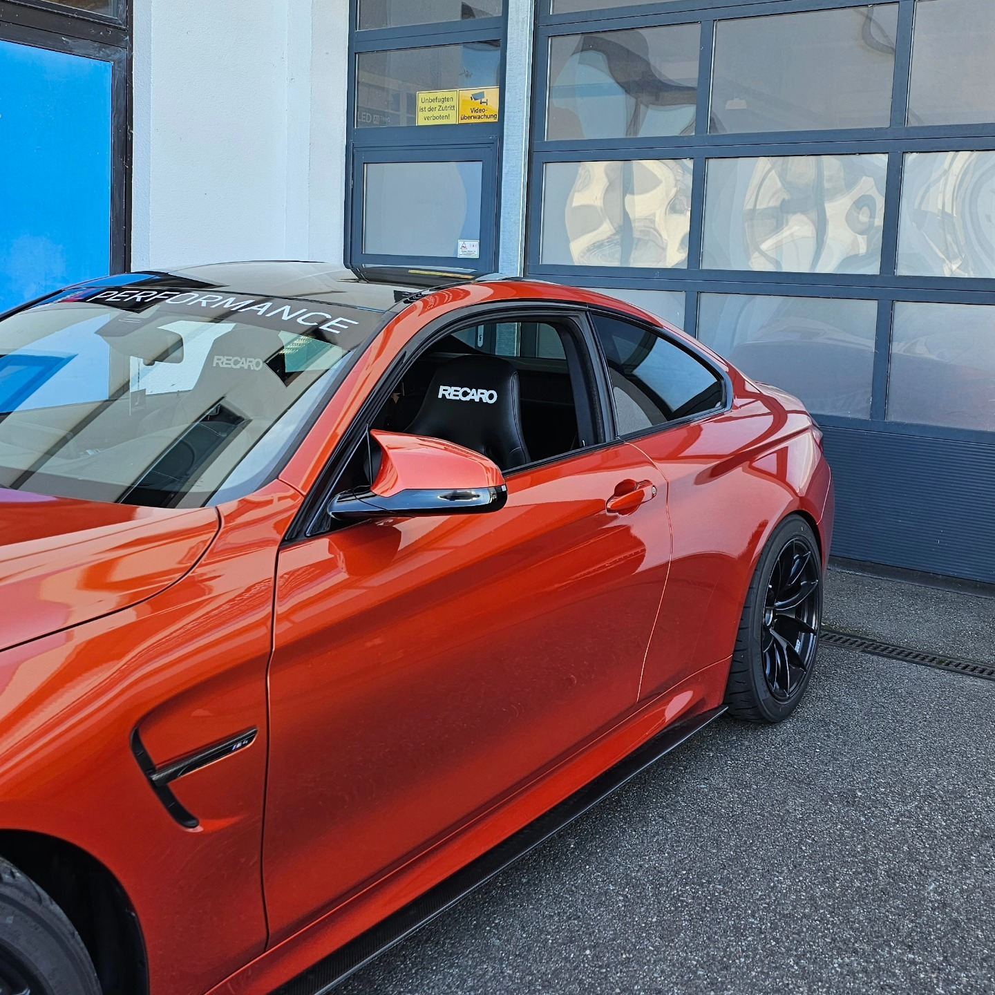Orangefarbener BMW M4 vor dem Rolltor