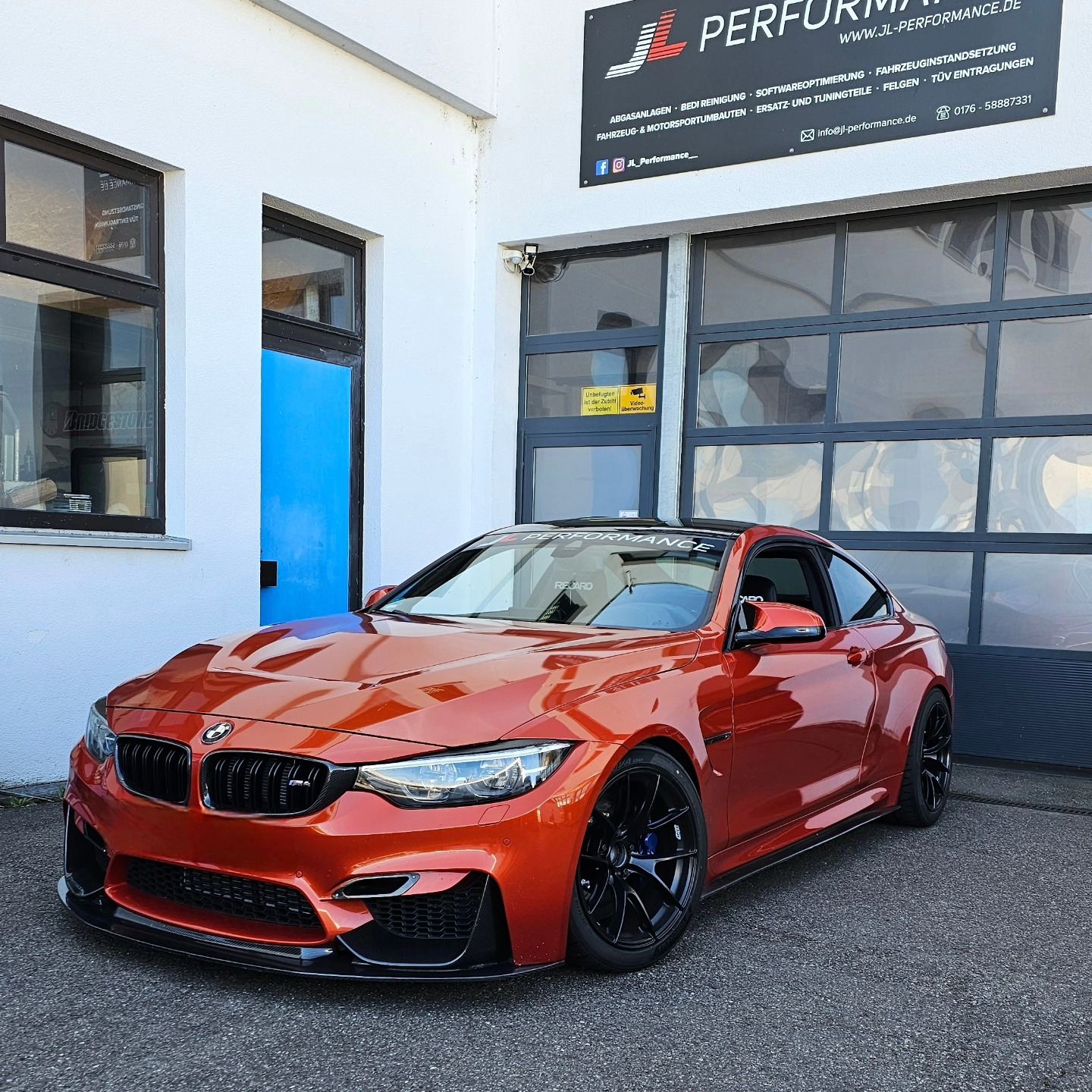 BMW M4 in Orange vor dem Firmenschild